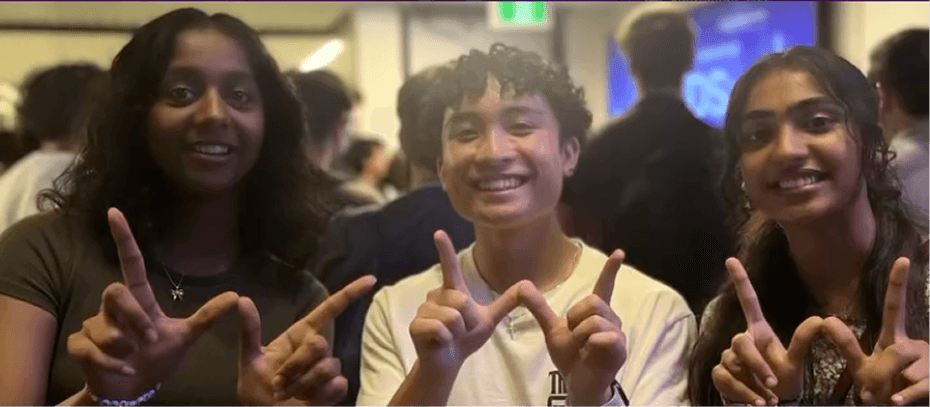 Students smiling and throwing up the W